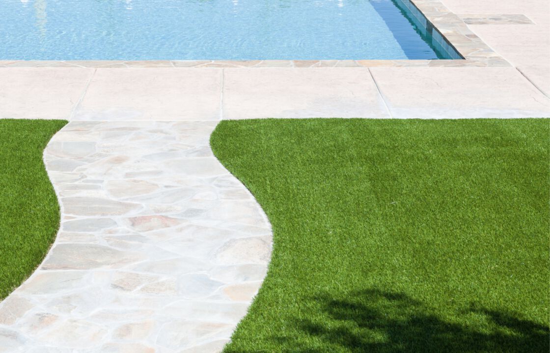 stone paver walkway to a pool surrounded by artificial grass